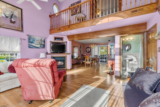 living room featuring a wealth of natural light, wood-type flooring, and a towering ceiling