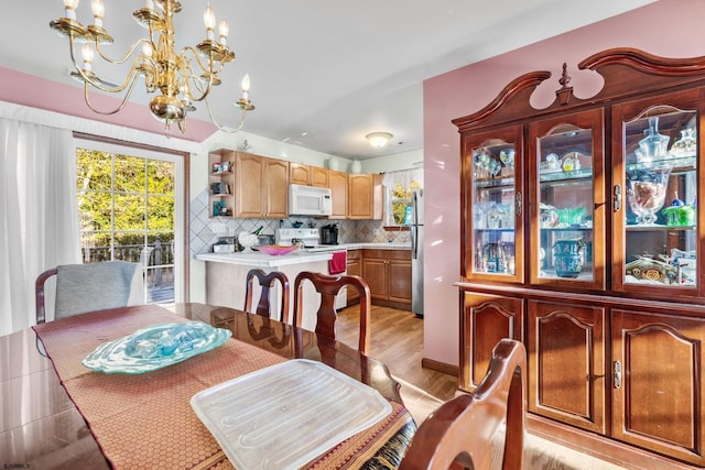 dining space featuring light wood-type flooring and a notable chandelier