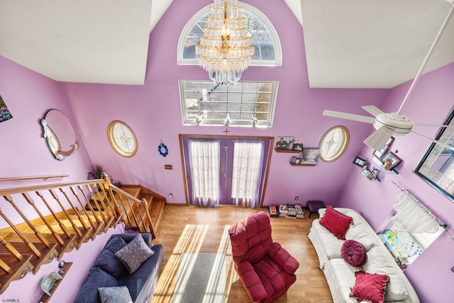 living room featuring a wealth of natural light, high vaulted ceiling, light hardwood / wood-style floors, and a notable chandelier