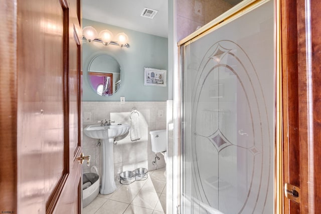 bathroom with toilet, tile walls, sink, and tile patterned floors