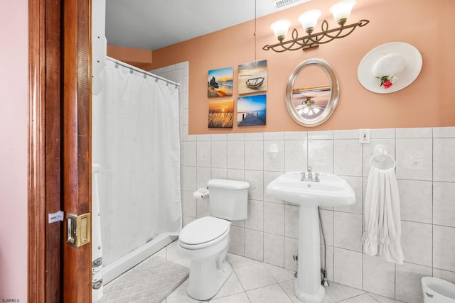 bathroom with tile walls, tile patterned flooring, walk in shower, and toilet