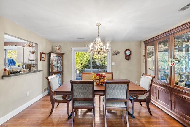 dining area with a notable chandelier and light hardwood / wood-style flooring