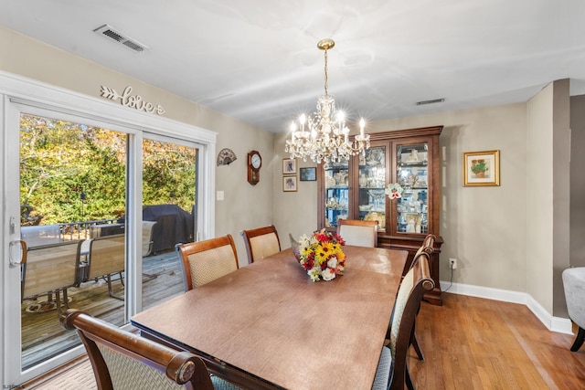 dining space with light wood-type flooring and a notable chandelier