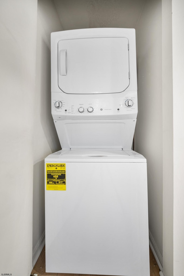 washroom with hardwood / wood-style floors and stacked washer / drying machine