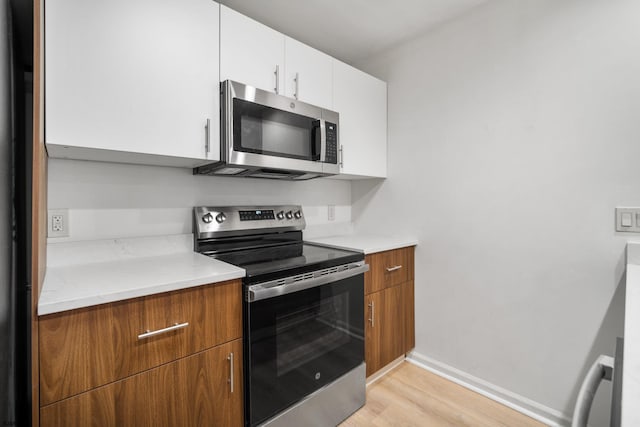 kitchen featuring stainless steel appliances, white cabinetry, and light hardwood / wood-style flooring