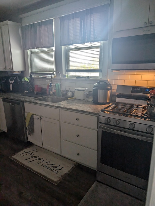 kitchen featuring decorative backsplash, sink, white cabinets, and appliances with stainless steel finishes