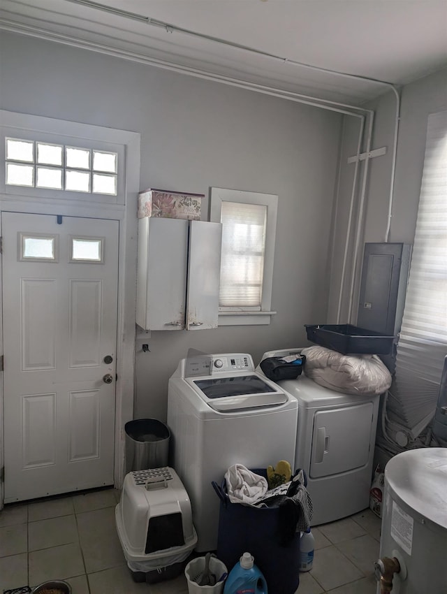 clothes washing area with light tile patterned floors, washer and clothes dryer, and water heater