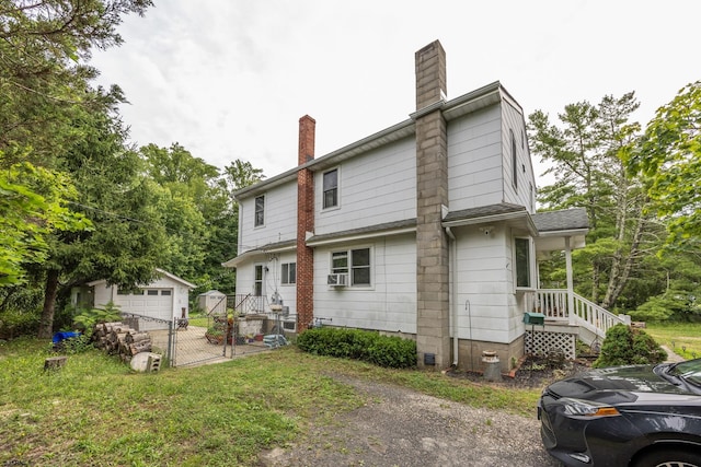 back of property with a garage, a yard, an outbuilding, and cooling unit