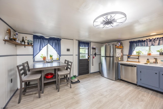 kitchen featuring stainless steel appliances, sink, backsplash, and light hardwood / wood-style flooring