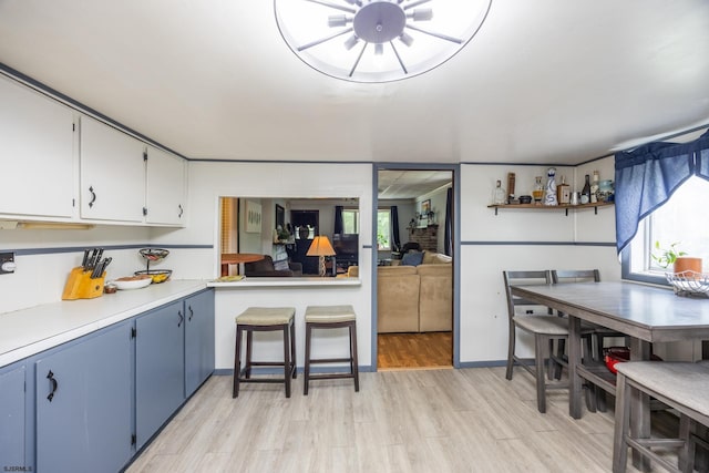 kitchen featuring blue cabinets, white cabinets, and light hardwood / wood-style floors