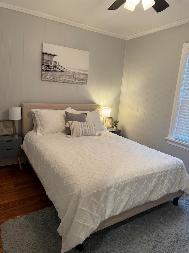 bedroom with dark hardwood / wood-style flooring, wooden walls, ceiling fan, and ornamental molding