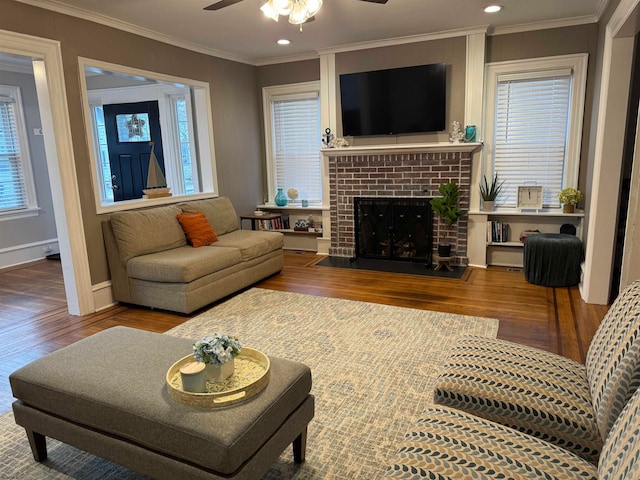 living room with crown molding, hardwood / wood-style floors, ceiling fan, and a brick fireplace