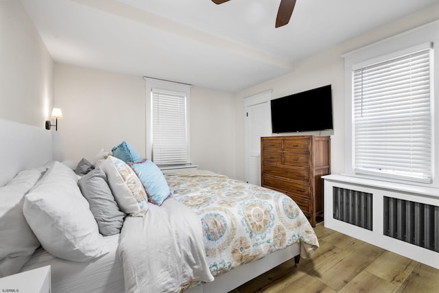 bedroom featuring ceiling fan, radiator heating unit, and light wood-type flooring