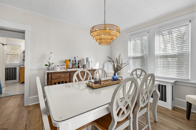 dining room with a notable chandelier, light wood-type flooring, and ornamental molding