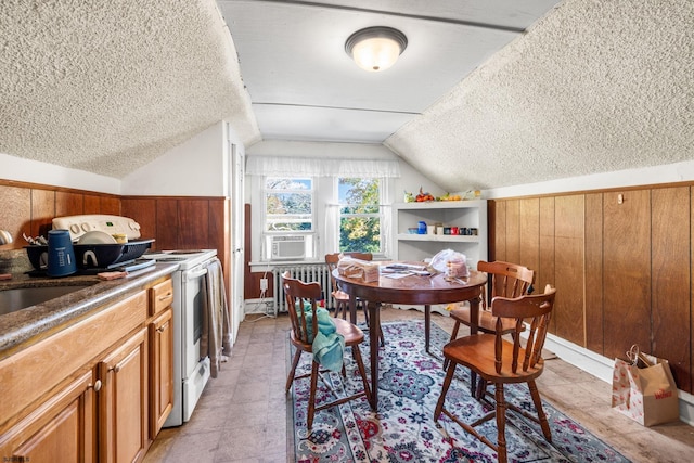 dining space featuring a textured ceiling, wooden walls, sink, radiator heating unit, and lofted ceiling