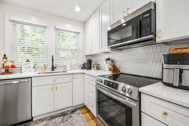 kitchen with white cabinets, decorative backsplash, sink, and stainless steel appliances