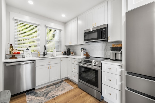 kitchen with white cabinets, light hardwood / wood-style floors, sink, and stainless steel appliances