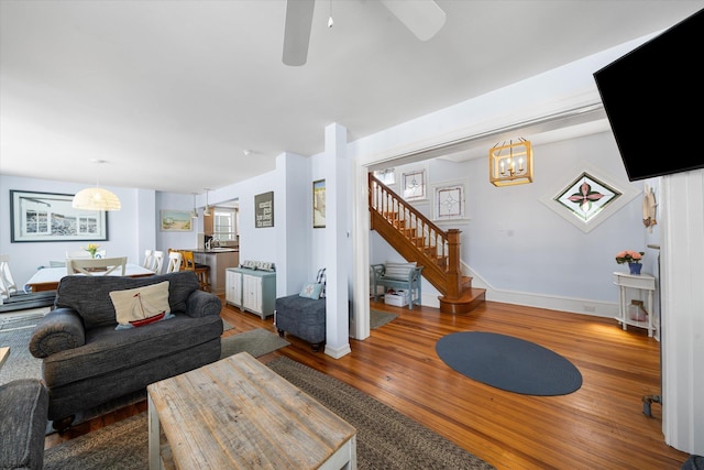 living room with ceiling fan with notable chandelier, hardwood / wood-style flooring, and sink