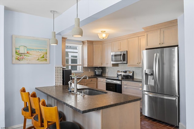 kitchen featuring sink, light brown cabinets, hanging light fixtures, a kitchen bar, and appliances with stainless steel finishes