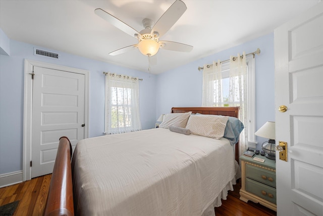 bedroom with multiple windows, ceiling fan, and dark hardwood / wood-style floors