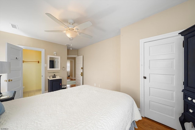 bedroom with connected bathroom, ceiling fan, and light wood-type flooring