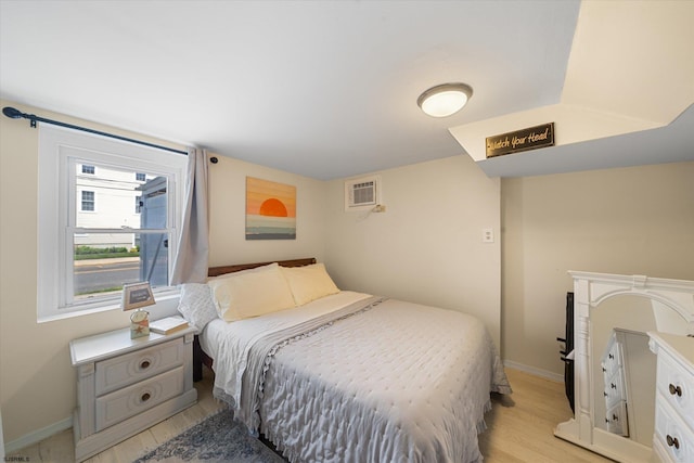 bedroom featuring a wall mounted air conditioner and light hardwood / wood-style flooring