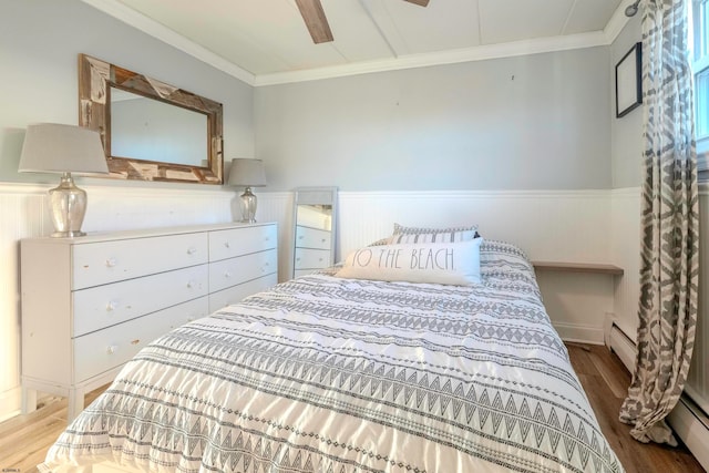 bedroom with ceiling fan, a baseboard radiator, and hardwood / wood-style flooring