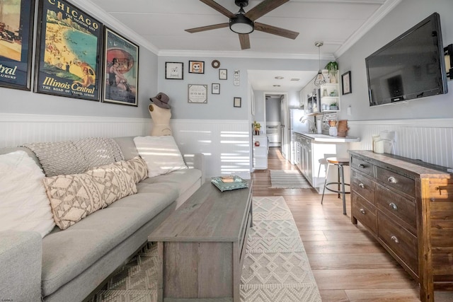 living room with light hardwood / wood-style flooring, ceiling fan, ornamental molding, and sink