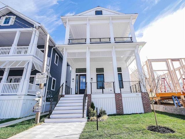 view of front facade with covered porch, a balcony, and a front lawn