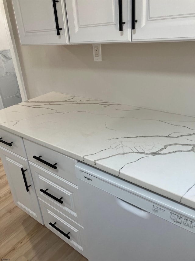 details featuring white dishwasher, white cabinetry, light stone counters, and light wood-type flooring