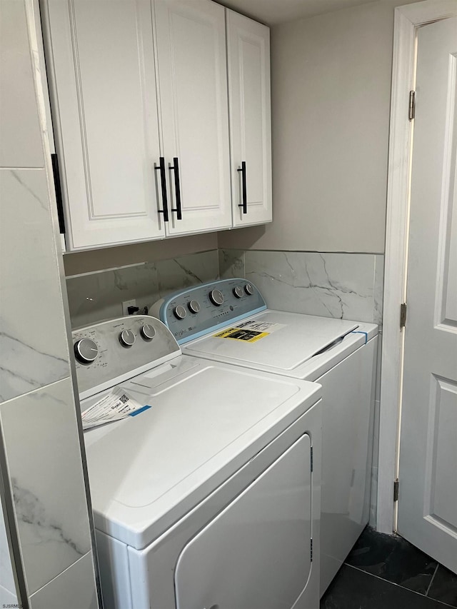 washroom with washing machine and clothes dryer, cabinets, and dark tile patterned flooring