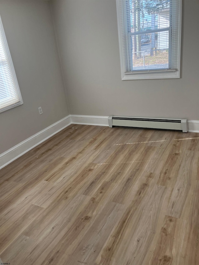 empty room featuring a baseboard radiator and light hardwood / wood-style flooring