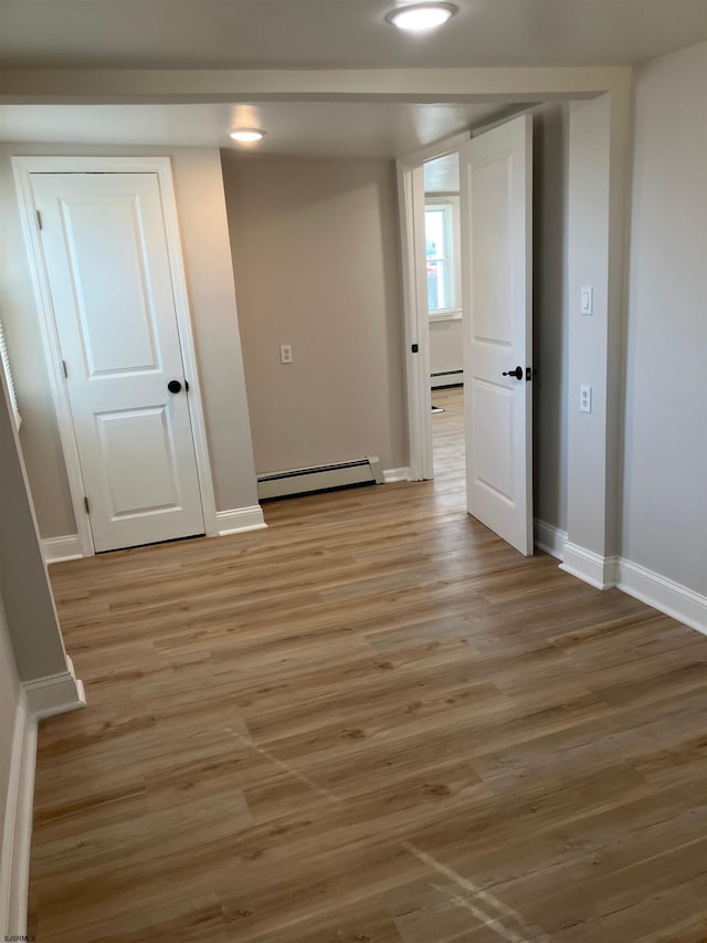 unfurnished room with light wood-type flooring and a baseboard radiator