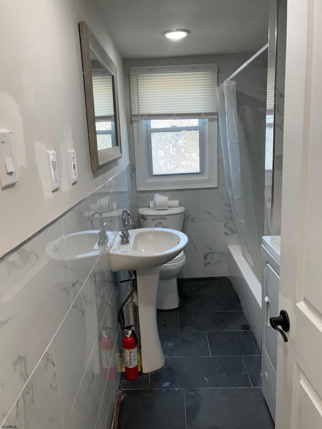 full bathroom featuring sink, toilet, tile walls, shower / tub combo, and washer / clothes dryer