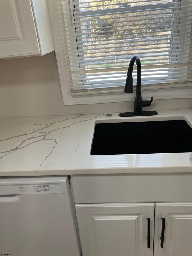 details featuring white cabinets, dishwasher, light stone counters, and sink