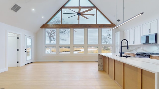 kitchen with light stone countertops, appliances with stainless steel finishes, sink, and high vaulted ceiling