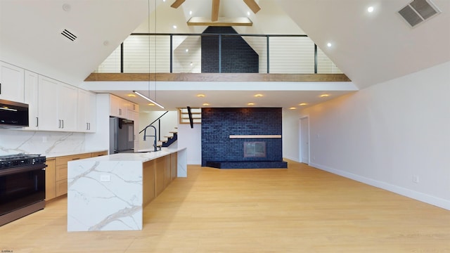 kitchen featuring a large island with sink, white cabinets, high vaulted ceiling, and black appliances