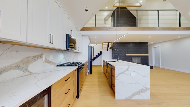 kitchen featuring stainless steel appliances, light wood-type flooring, white cabinets, and light stone counters