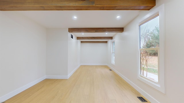 unfurnished room with beamed ceiling and light hardwood / wood-style flooring