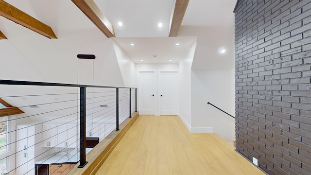 hallway featuring beam ceiling, brick wall, mail boxes, and light wood-type flooring