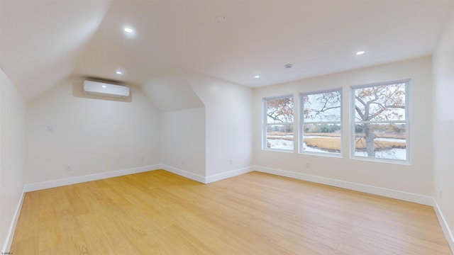 bonus room with an AC wall unit, lofted ceiling, and light hardwood / wood-style floors