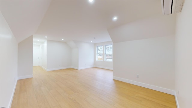 additional living space with an AC wall unit and light wood-type flooring