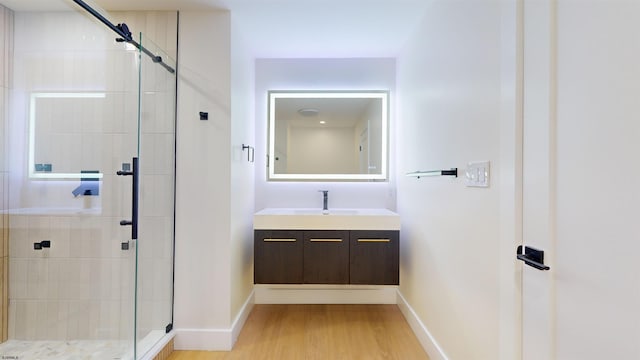 bathroom with walk in shower, vanity, and hardwood / wood-style floors