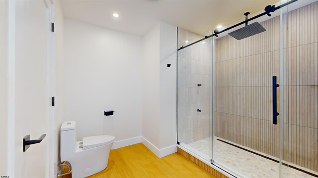 bathroom with hardwood / wood-style flooring, walk in shower, and toilet