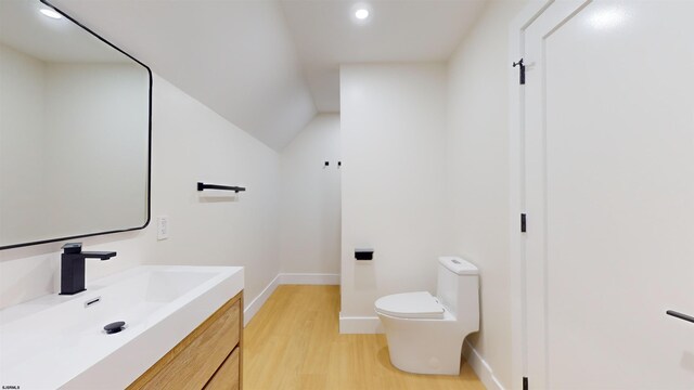 bathroom featuring vanity, wood-type flooring, toilet, and vaulted ceiling