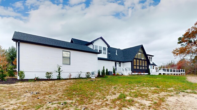 back of house featuring a sunroom, central AC unit, and a lawn