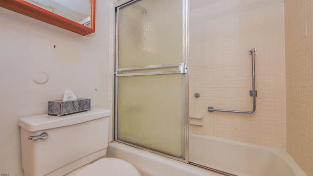 bathroom featuring combined bath / shower with glass door and toilet