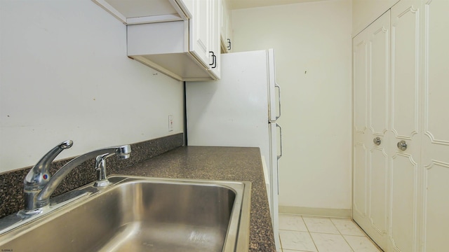 kitchen with white cabinets, light tile patterned floors, and sink