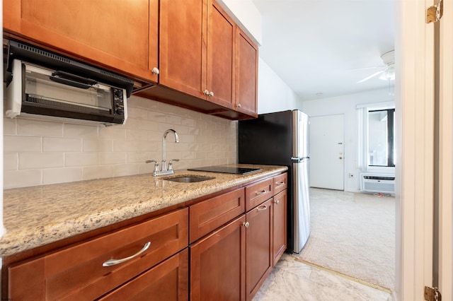 kitchen with backsplash, an AC wall unit, sink, light stone countertops, and stainless steel refrigerator