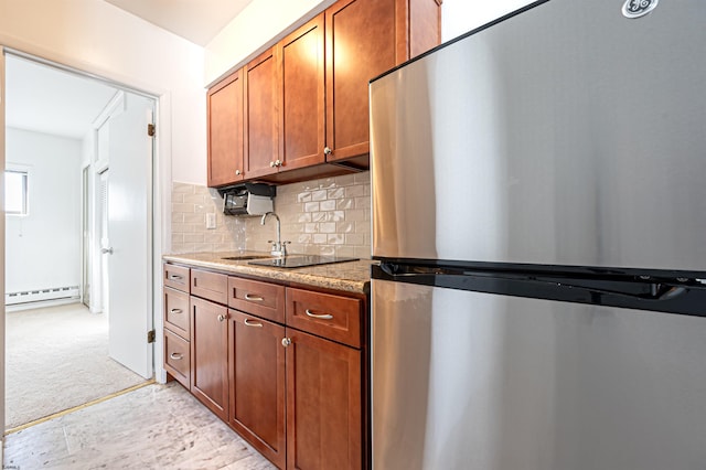 kitchen with stainless steel fridge, backsplash, light colored carpet, a baseboard heating unit, and stone counters